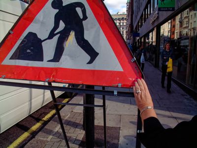 Red. Hand resting on a road works sign