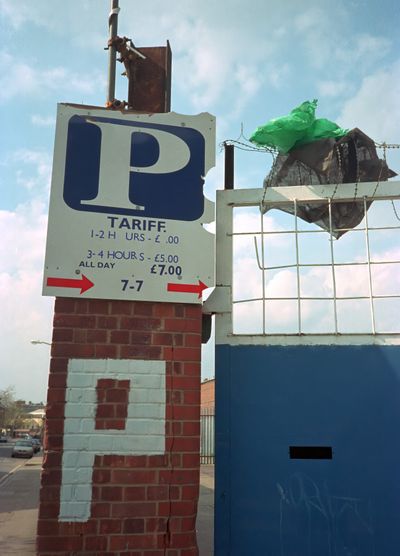 Parking signs and a plastic bag caught on a fence